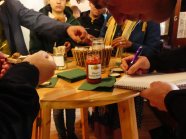 Glas Kürbis-Chutney am Tisch rundherum sitzen Meisterschüler die Notizen machen und verkosten